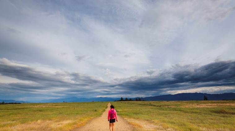 Wide shot of a woman hiking on a trail