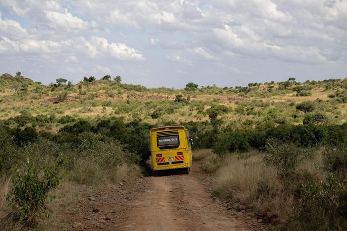 A schoolbus drives down a dirt road into the Loisaba preserve.